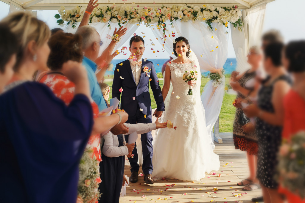 Stylish happy smiling newlyweds on the luxury outdoor wedding ceremony in haze tent near the ocean