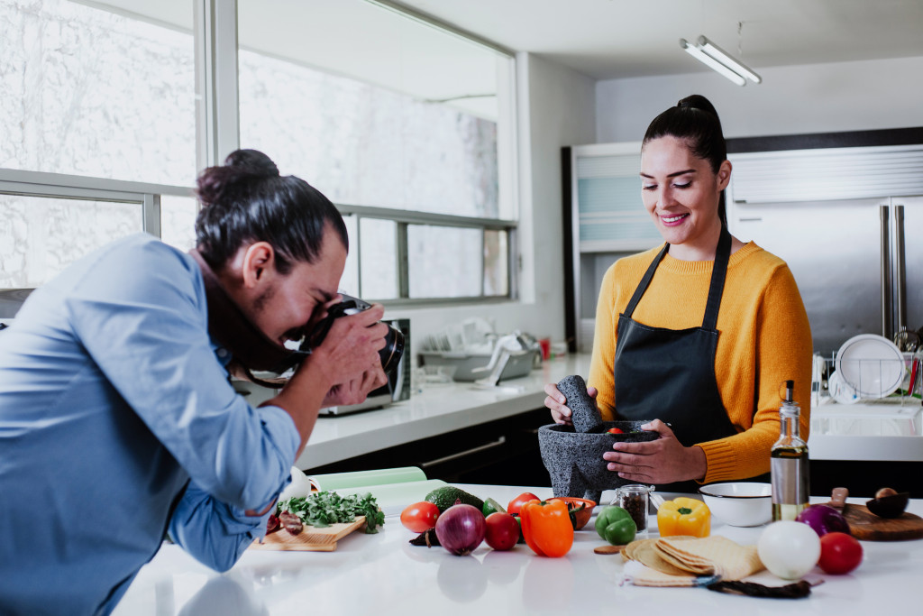 a man taking photos of a woman while cooking in the kitchen